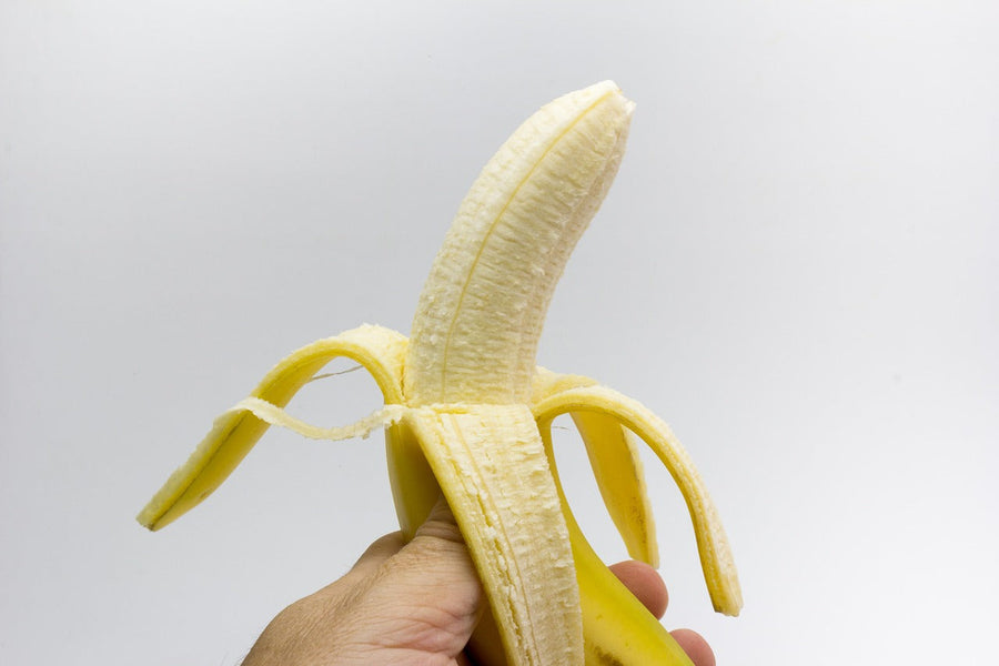 Hand die een gepelde banaan vasthoudt